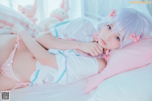 A woman in a pink dress sitting on a bed with stuffed animals.