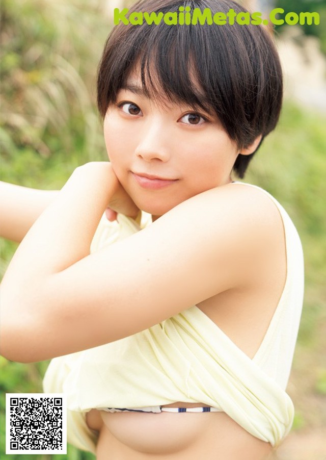 A woman in a yellow top is posing for a picture.