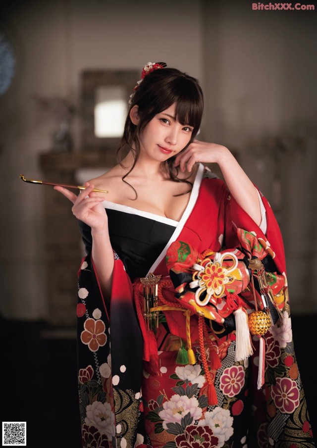 A woman in a kimono holding a stick in her hand.