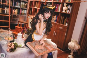 A woman standing in front of a bookshelf holding a book.