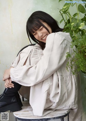 A woman in a white shirt and white shorts leaning against a ladder.