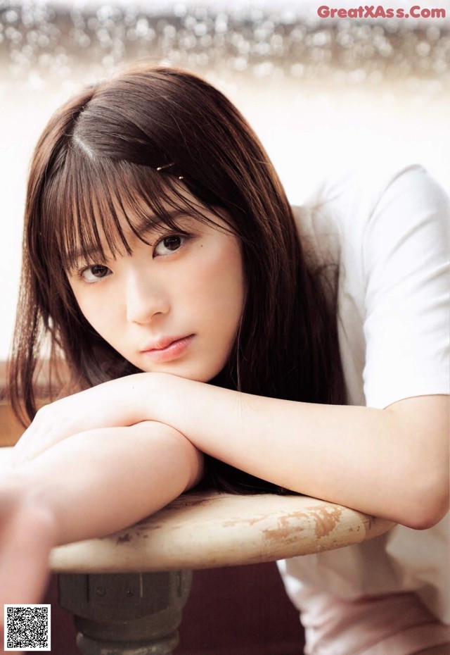 A young woman sitting on top of a wooden table.