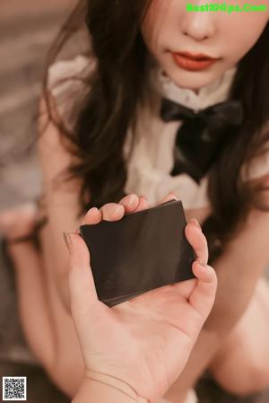 A woman in a maid outfit sitting on the floor.