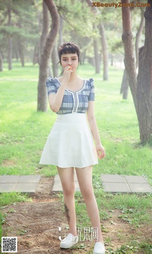 A woman sitting on a wooden bench in a park.