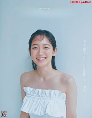 A woman in a white dress smiling at the camera.