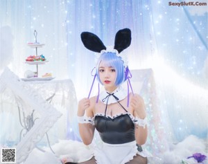 A woman in a bunny costume sitting on a bed.