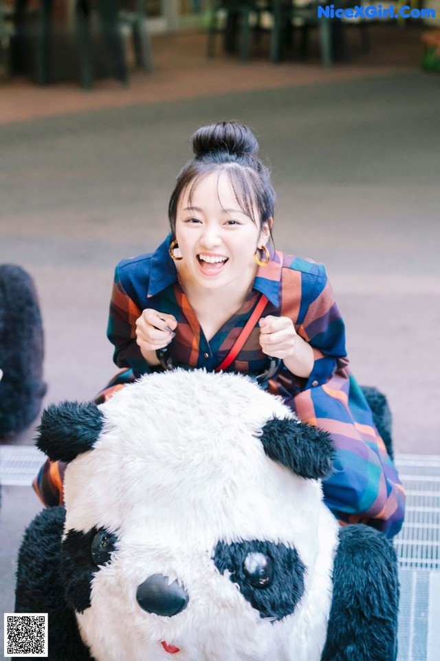 A woman sitting on top of a stuffed panda bear.