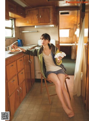 A woman sitting on top of a bed with her legs crossed.