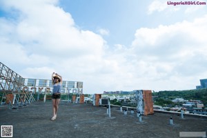 A woman in camouflage shorts and a straw hat leaning against a ladder.