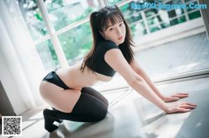A woman in a black shirt and black stockings posing for a picture.