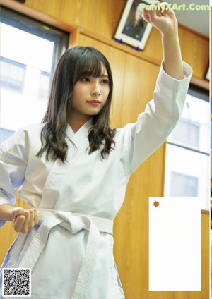 A woman in a white kimono is practicing karate. 