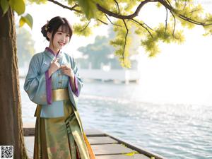 A woman in a yellow kimono sitting on a white table.