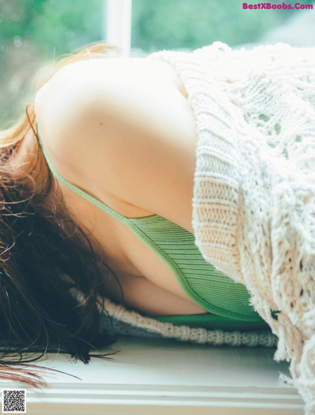 A woman laying on a window sill with her back to the camera.