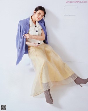 A woman in a beige blazer and pink shirt posing for a magazine.