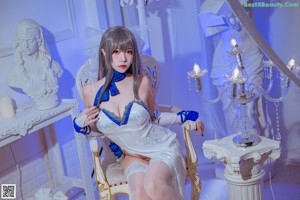 A woman in a white and blue lingerie sitting on a chair.