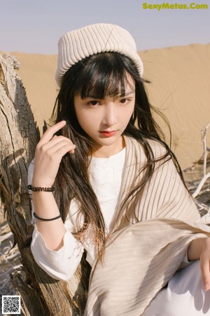 A woman in a white dress laying on a sand dune.