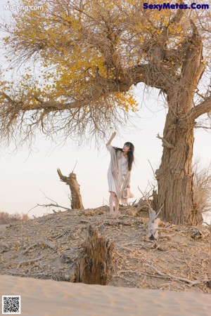 A woman sitting on top of a sand dune in the desert.