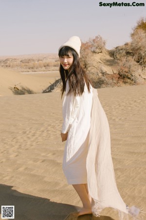 A woman with long brown hair sitting on a beach.