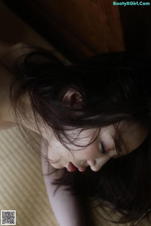 A naked woman laying on the floor in front of a wooden wall.