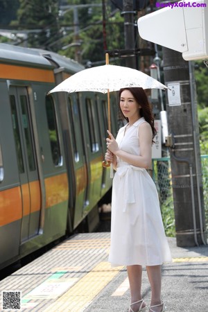 A woman with her eyes closed holding an umbrella.