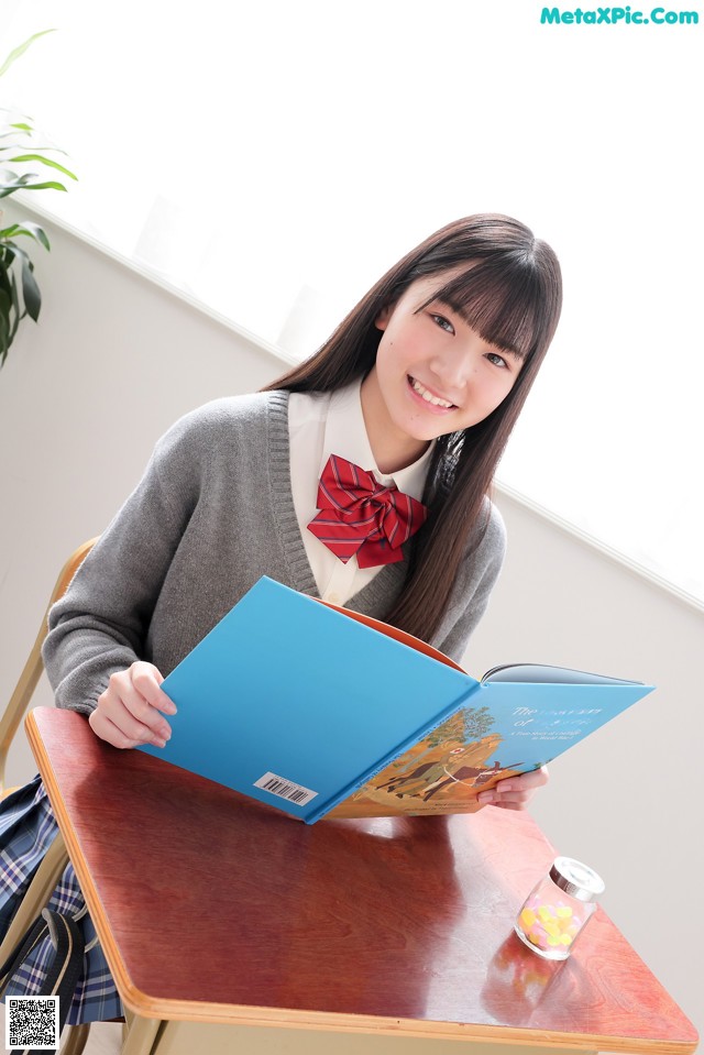 A young woman sitting at a table reading a book.