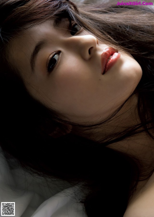 A woman laying on top of a bed with long black hair.