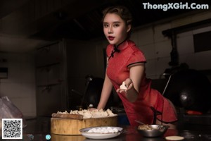 A woman in a red cheongsam preparing food in a kitchen.