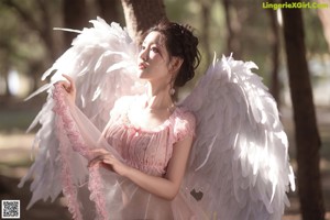 A woman in a pink dress with white wings.