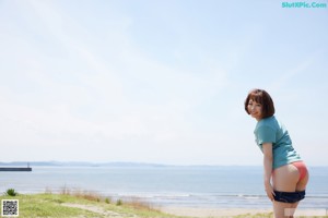 A woman in a bikini standing on a stone wall.