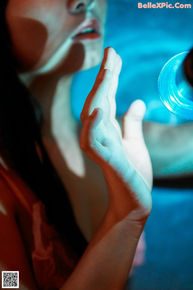 A woman holding a glass of water in her hand.