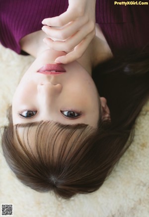A woman sitting on a wooden floor with her legs crossed.