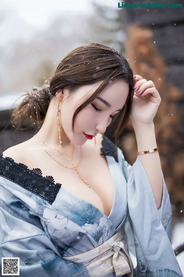 A woman in a blue kimono is posing for a picture.