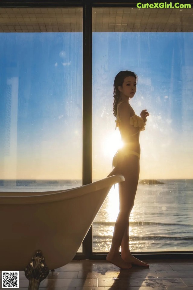 A woman standing in front of a bathtub in a bathroom.