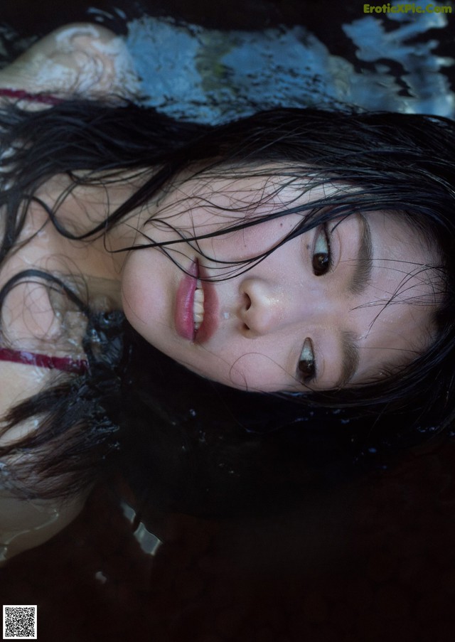 A woman with long black hair laying in the water.