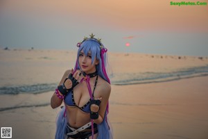 A woman with long blue hair standing on a beach.