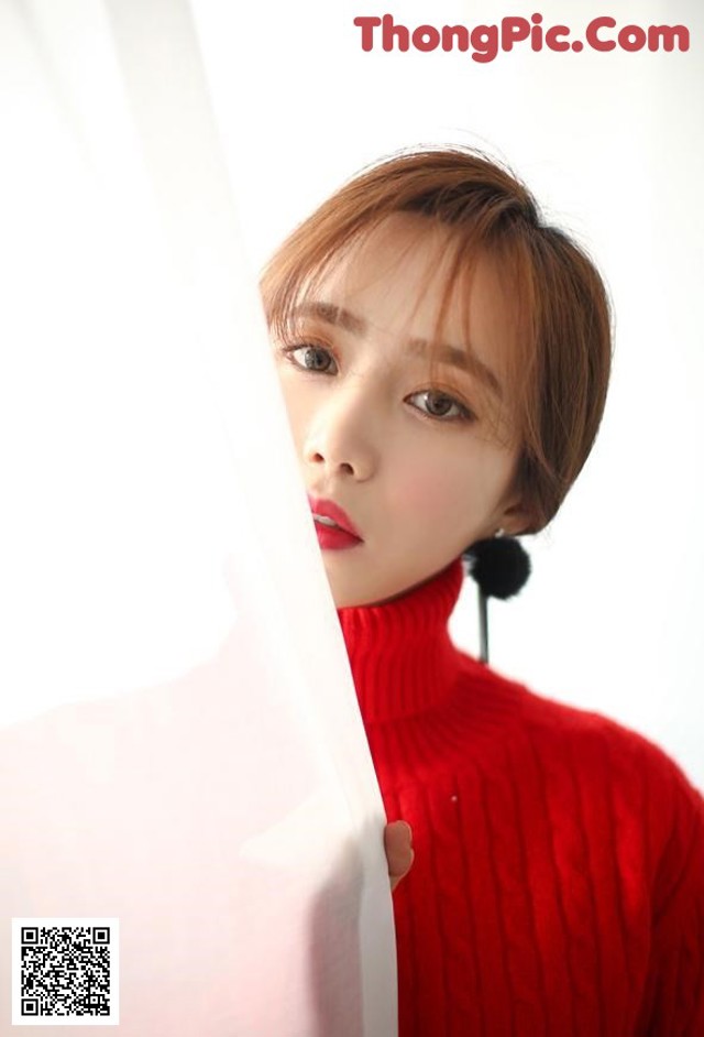 a woman in a red sweater holding a piece of paper