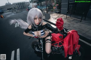 A woman sitting on a red motorcycle in the rain.