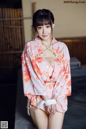 A woman in a pink kimono is tied up in a bathtub.