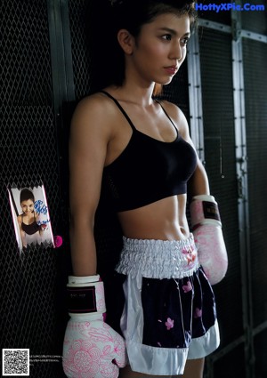 A woman in a bikini and boxing gloves posing for a picture.