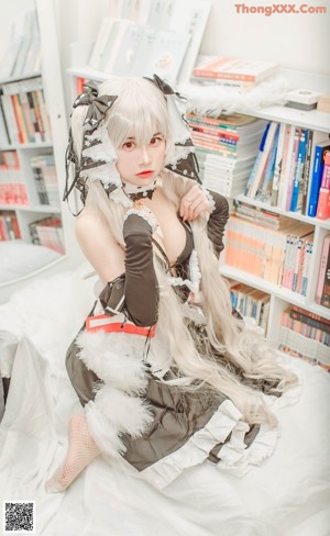 A woman sitting on top of a bed next to a book shelf.