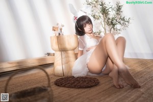 A woman in a white dress and bunny ears sitting on the floor.