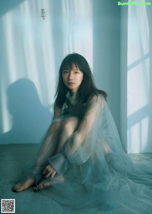 A woman sitting on the floor in a blue dress.