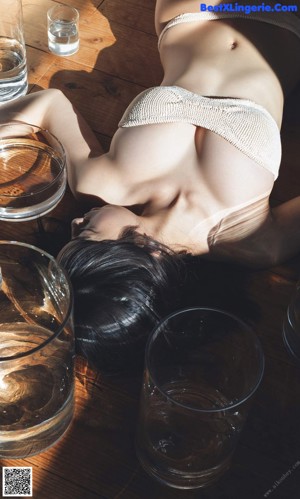 A woman sitting on the floor holding a glass of water.