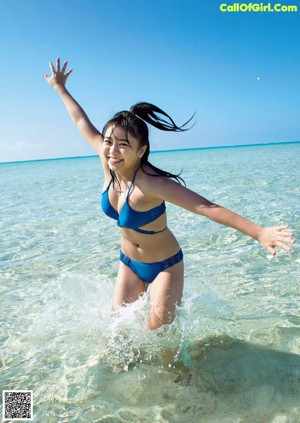 A woman in a bikini sitting on the beach.