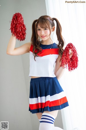 A woman in a cheerleading uniform sitting on a bed.