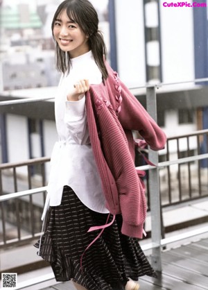 A woman standing in front of a window wearing a white shirt.