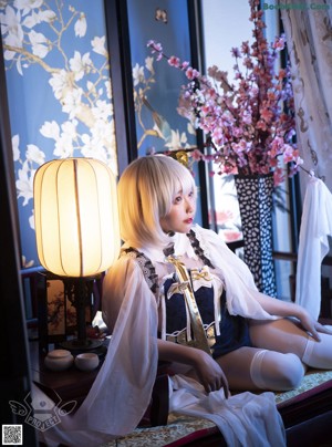 A woman sitting on top of a bed next to a lamp.