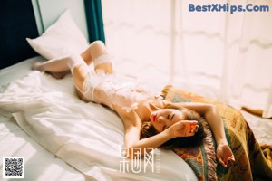 A woman sitting on top of a bed next to a window.