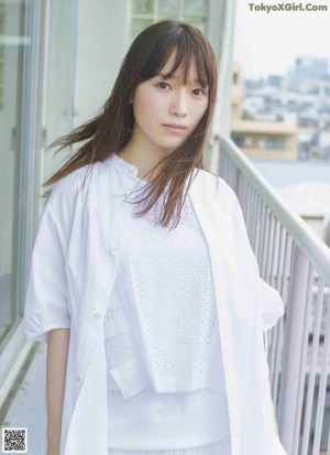 A woman in a white dress standing on top of a roof.