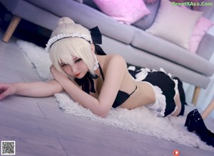 A woman in a maid outfit sitting on a couch.